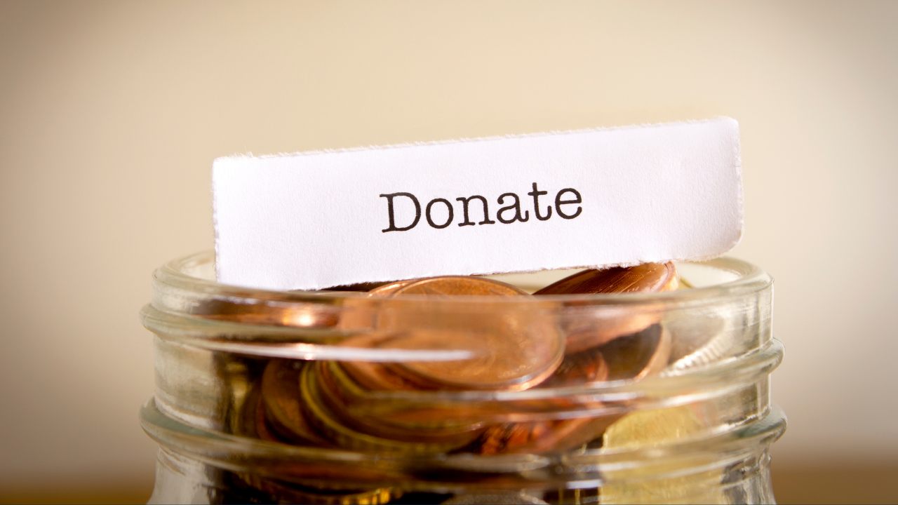 Image of a coin jar with a note saying "donate" on a beige background