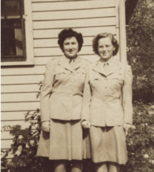Photo of two women in service uniforms standing in front of a building